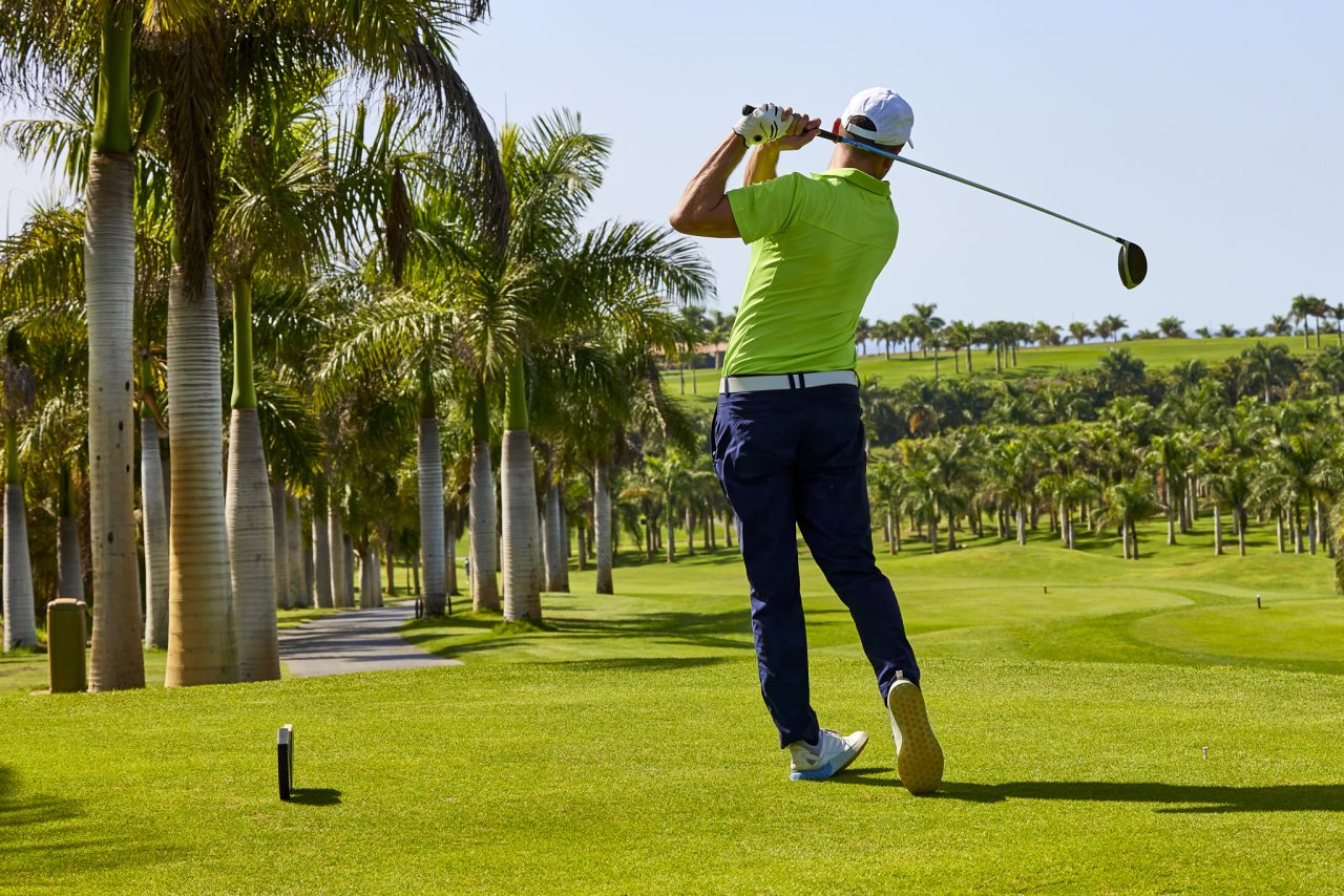 Golfer on a golf course, ready to tee off. Golfer with golf club hitting the ball for the perfect shot.