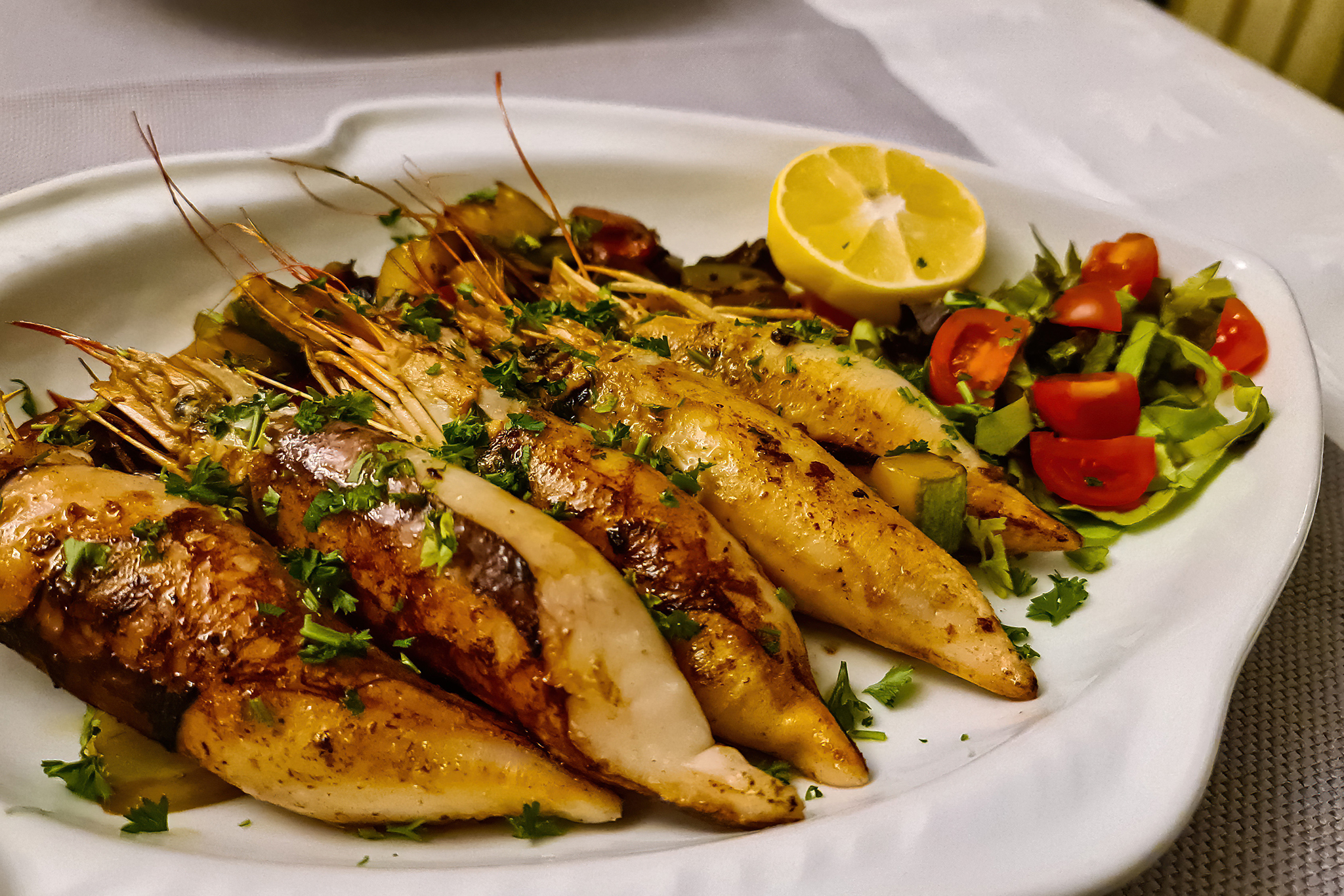 Plate of grilled squid with fresh lemon served in local restaurant in coastal village Sveti Stefan, Budva Riviera, Adriatic Mediterranean Sea, Montenegro, Europe. Local traditional sea food
